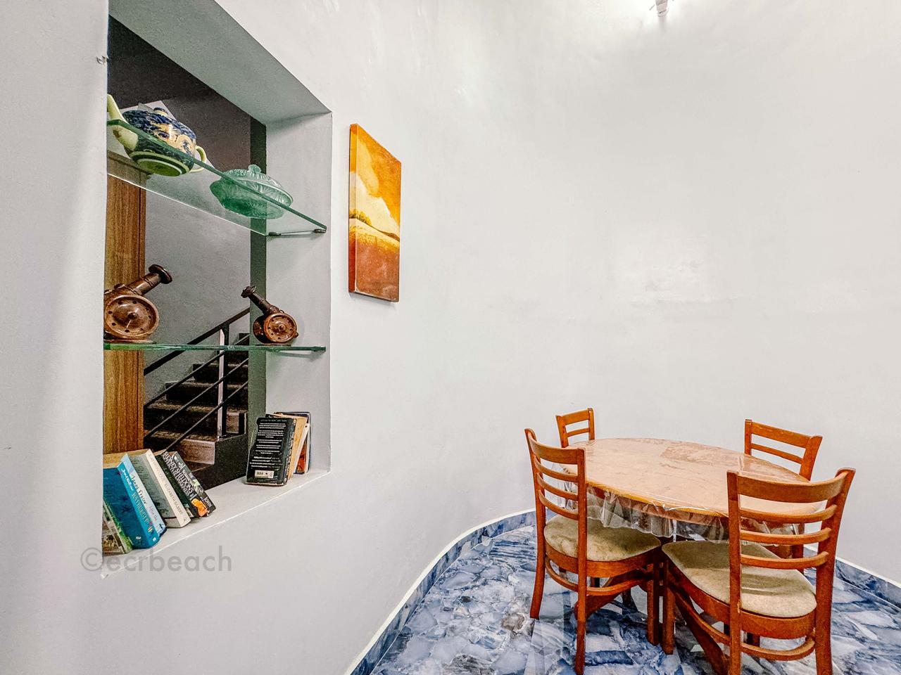 A cozy dining area featuring a round wooden table with chairs beside a decorative wall niche.