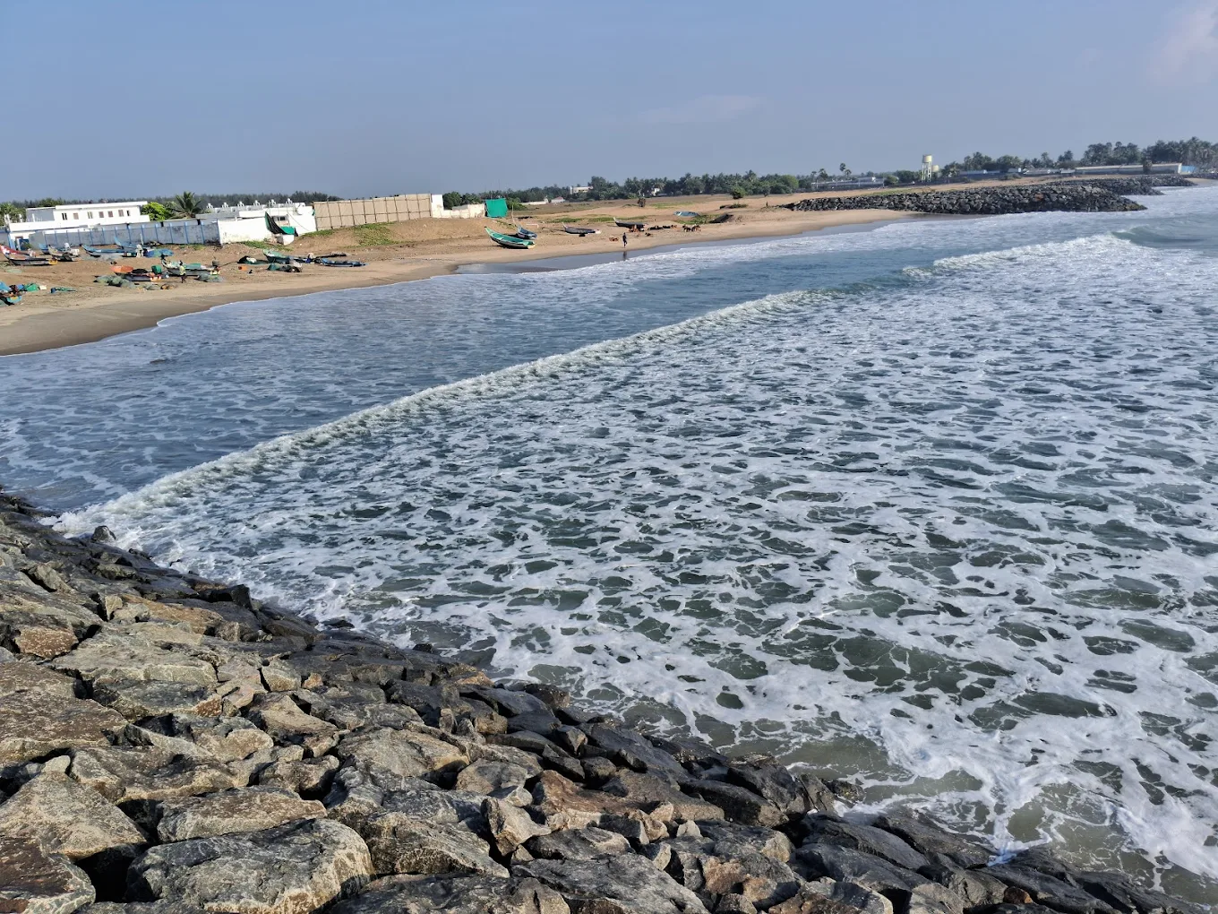 A scenic view of ocean waves breaking against a rocky shoreline and sandy beach.
