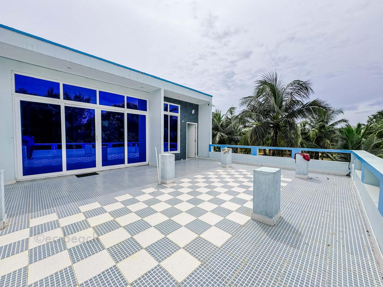 A spacious rooftop terrace with blue-tinted sliding glass doors and checkered tile flooring.