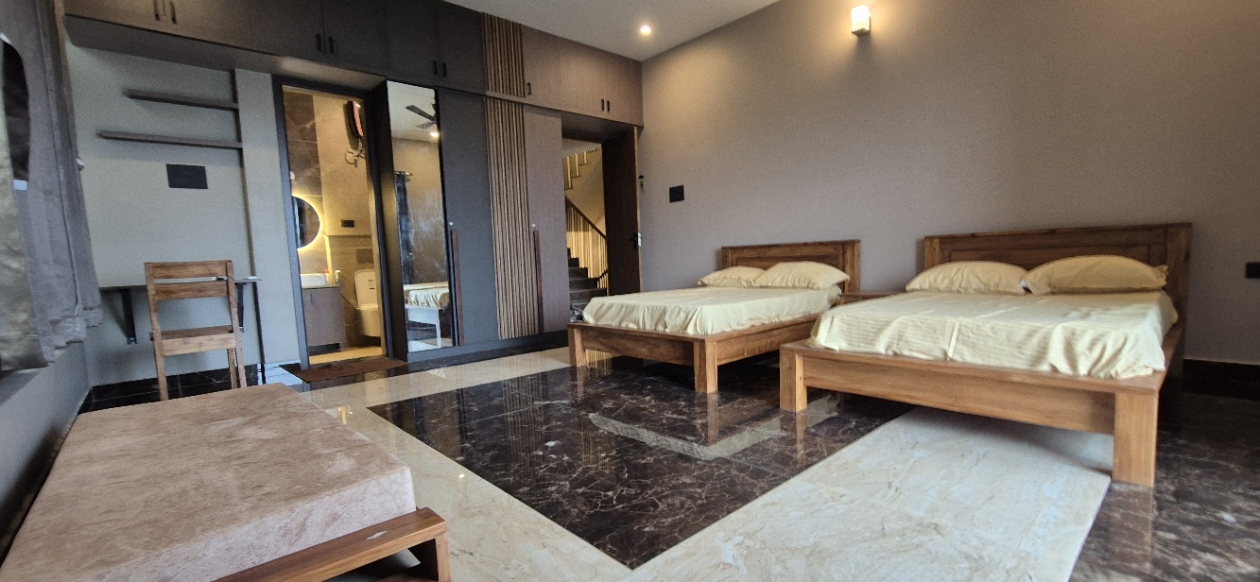 A spacious bedroom featuring two wooden double beds, built-in wardrobes, and shiny tile flooring.