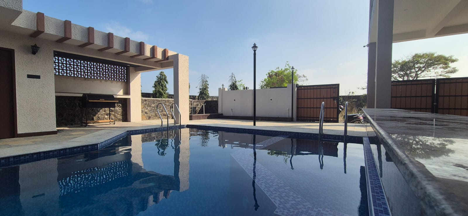 An outdoor swimming pool at a private villa under a clear blue sky.
