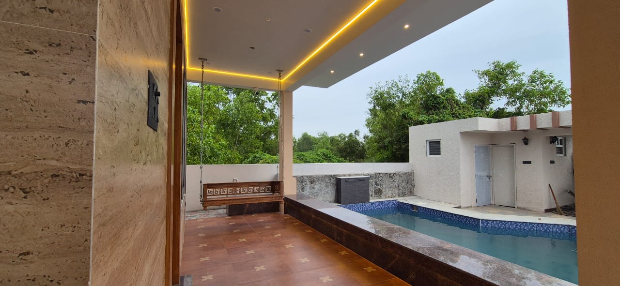 A covered patio with a wooden swing bench next to a private swimming pool.